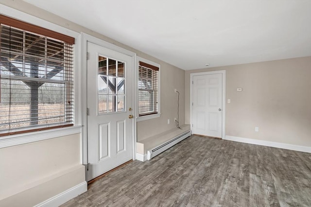interior space featuring baseboards, a baseboard heating unit, a wealth of natural light, and wood finished floors