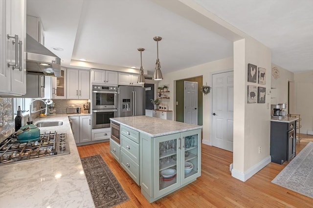 kitchen featuring light wood-style floors, a sink, ventilation hood, and stainless steel appliances