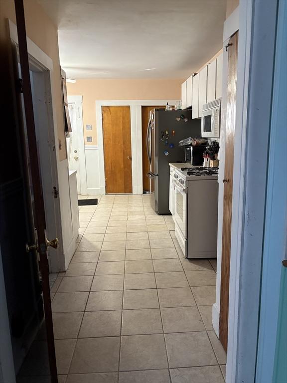 kitchen with light tile patterned flooring, white appliances, and white cabinets