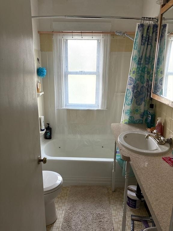 full bathroom with a healthy amount of sunlight, toilet, tile patterned flooring, and shower / bath combo with shower curtain