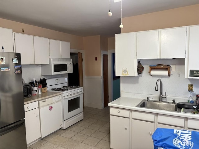 kitchen featuring white appliances, light tile patterned floors, sink, and white cabinets