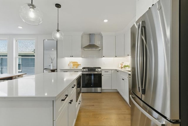 43-45 Wellington St Unit 2, Waltham, MA 02451 - kitchen with stainless steel appliances, wall chimney exhaust hood, light countertops, decorative light fixtures, and tasteful backsplash