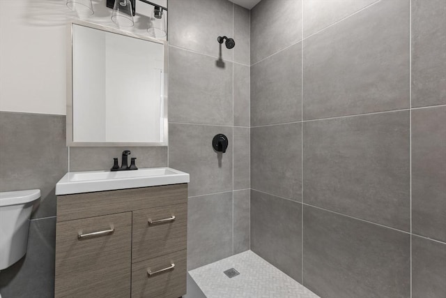 full bathroom featuring toilet, a tile shower, and vanity