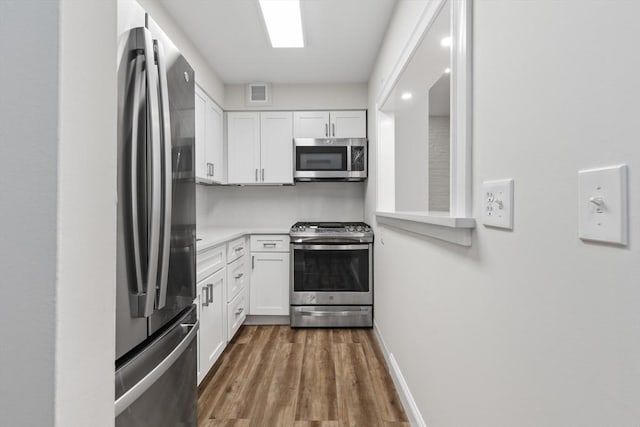 kitchen with visible vents, appliances with stainless steel finishes, wood finished floors, light countertops, and white cabinetry