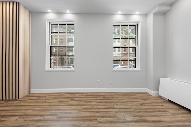 unfurnished room with baseboards, wood finished floors, and recessed lighting