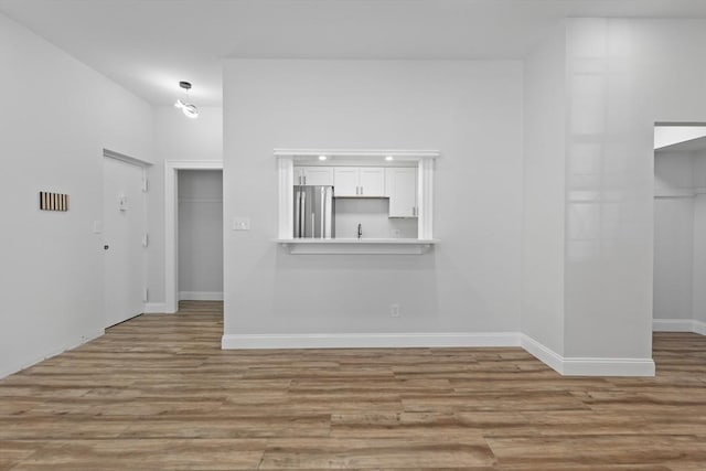 unfurnished living room featuring wood finished floors and baseboards