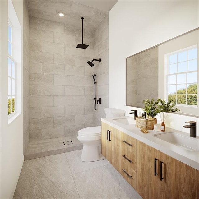 bathroom featuring a tile shower, a sink, and a wealth of natural light