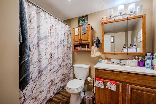 full bath featuring toilet, wood finished floors, vanity, and curtained shower