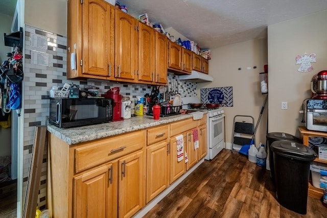 kitchen featuring white gas range, black microwave, under cabinet range hood, dark wood-style flooring, and tasteful backsplash