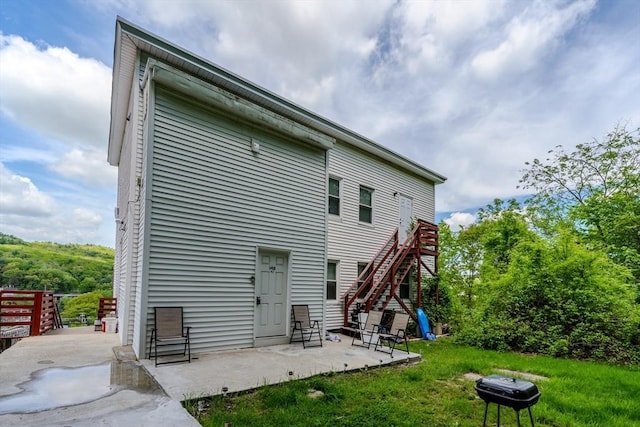 back of house with a patio, stairway, and a yard