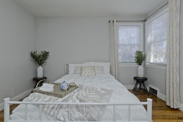 bedroom with visible vents, baseboards, and wood finished floors