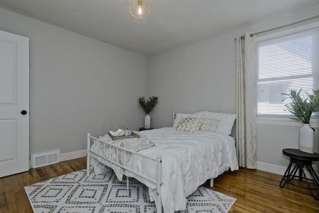 bedroom featuring baseboards, visible vents, and wood finished floors