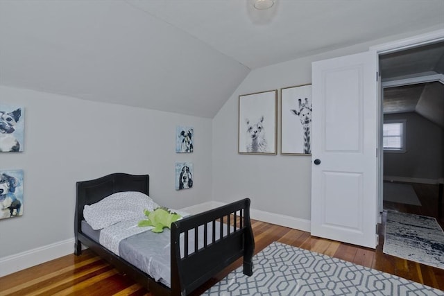 bedroom with vaulted ceiling, hardwood / wood-style floors, and baseboards