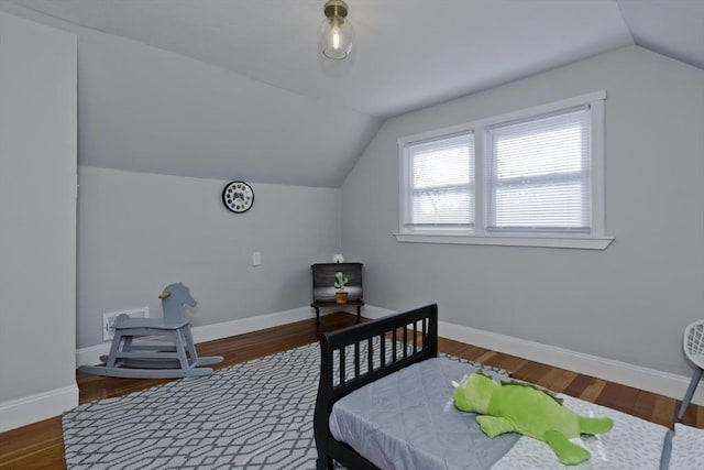 bedroom with baseboards, vaulted ceiling, and wood finished floors