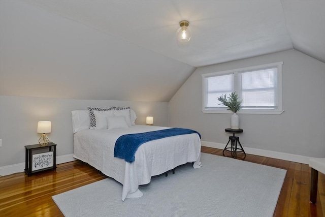 bedroom with hardwood / wood-style flooring, baseboards, and vaulted ceiling