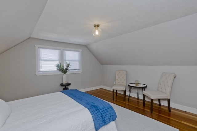 bedroom featuring lofted ceiling, wood finished floors, and baseboards