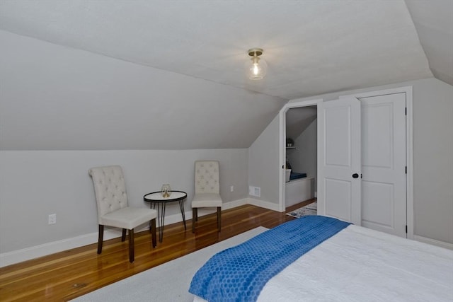 bedroom with lofted ceiling, visible vents, baseboards, and wood finished floors