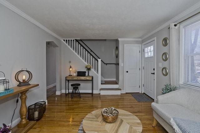 foyer with wood finished floors, crown molding, baseboards, and stairs