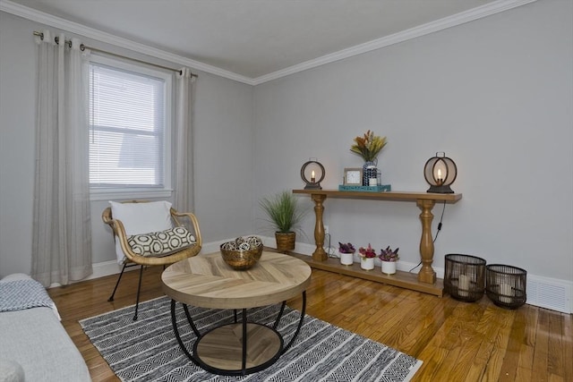 living area with visible vents, crown molding, baseboards, and wood finished floors