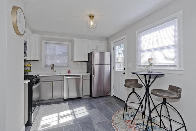 kitchen featuring appliances with stainless steel finishes, backsplash, light countertops, white cabinetry, and a sink