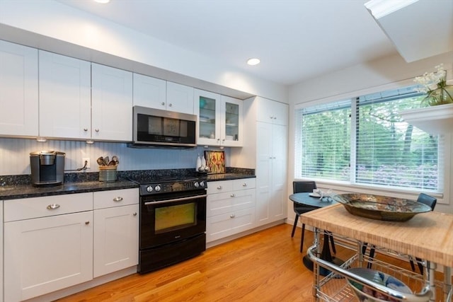 1175 Chestnut St Unit 33, Newton, MA 02464 - kitchen featuring stainless steel microwave, black electric range, white cabinets, light wood-style floors, and dark stone countertops