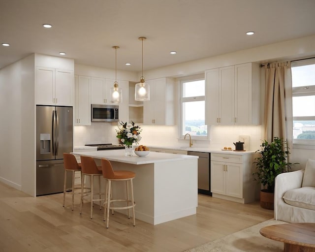 kitchen featuring white cabinets, tasteful backsplash, appliances with stainless steel finishes, and a kitchen island