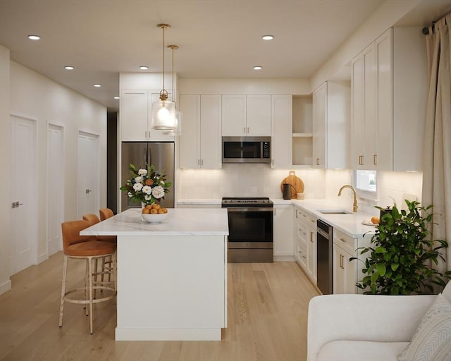 kitchen featuring a sink, stainless steel appliances, white cabinets, and a center island