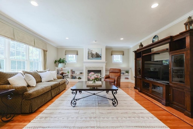 living room with plenty of natural light, ornamental molding, and light wood finished floors