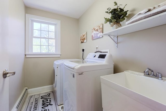 laundry area with laundry area, baseboards, baseboard heating, washing machine and clothes dryer, and a sink