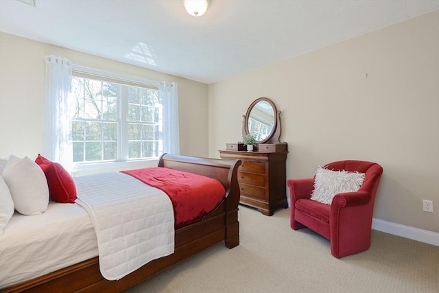 bedroom featuring baseboards, multiple windows, and light carpet