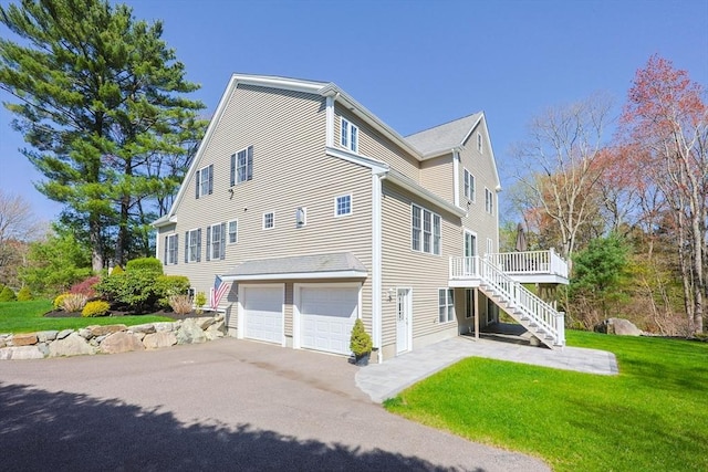 view of home's exterior featuring driveway, a deck, a garage, stairway, and a yard