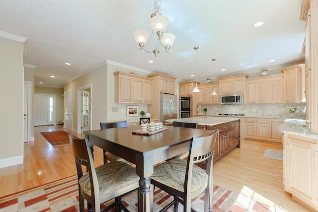 kitchen with crown molding, appliances with stainless steel finishes, light wood-style floors, decorative backsplash, and a kitchen island
