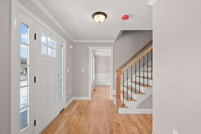 foyer entrance with ornamental molding and light wood-type flooring