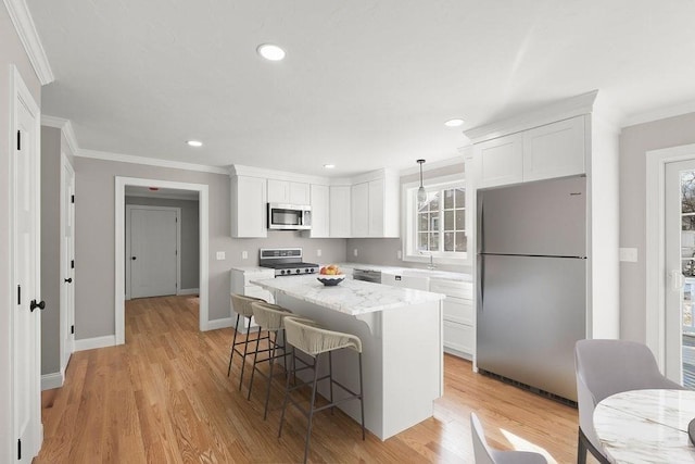 kitchen with decorative light fixtures, white cabinetry, a breakfast bar area, stainless steel appliances, and crown molding