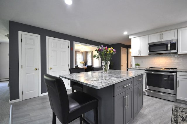 3 Cornet Stetson, Rockland, MA 02370 - kitchen featuring appliances with stainless steel finishes, a kitchen bar, backsplash, light stone countertops, and recessed lighting