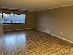 empty room with hardwood / wood-style floors and ornamental molding