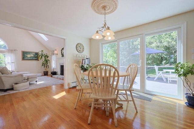 2 David Henry Gardner Ln, Southborough, MA 01772 - dining space with light wood-style floors, vaulted ceiling, a brick fireplace, a skylight, and a baseboard heating unit