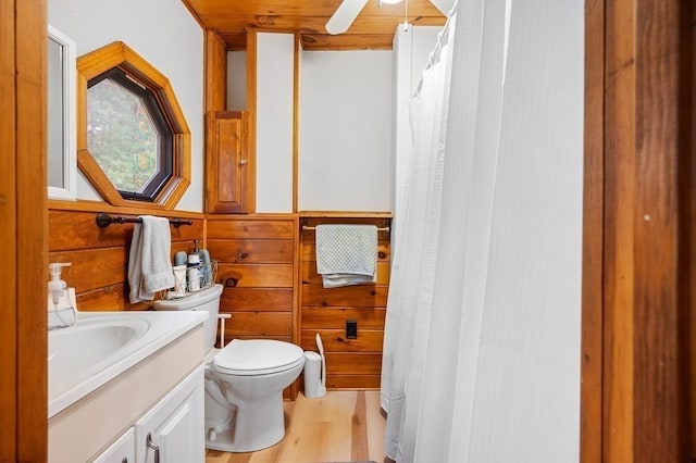 bathroom featuring vanity, wood walls, wooden ceiling, toilet, and wood-type flooring