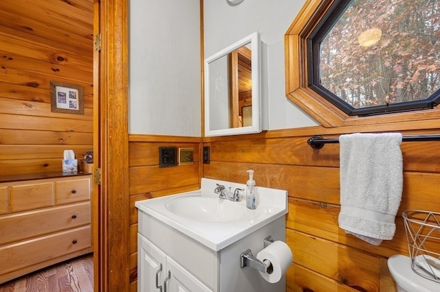 bathroom with vanity, toilet, and wooden walls