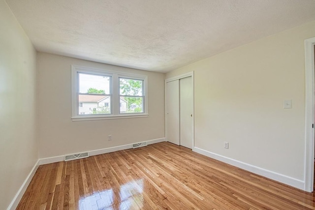 143 Ryan Rd, Stoughton, MA 02072 - unfurnished bedroom featuring light wood-style flooring, baseboards, a closet, and a textured ceiling