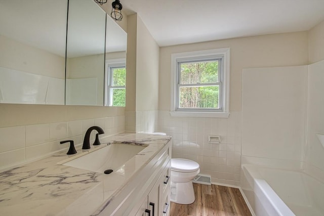 143 Ryan Rd, Stoughton, MA 02072 - bathroom featuring tile walls, vanity, toilet, wood finished floors, and wainscoting
