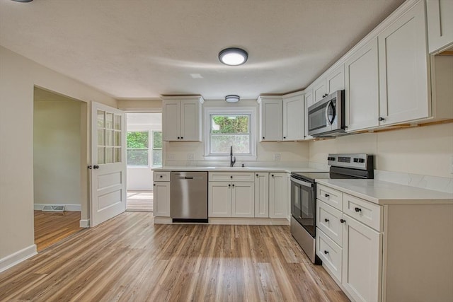 143 Ryan Rd, Stoughton, MA 02072 - kitchen featuring appliances with stainless steel finishes, a sink, light wood-style flooring, light countertops, and baseboards