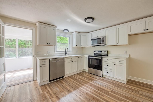 143 Ryan Rd, Stoughton, MA 02072 - kitchen with stainless steel appliances, a sink, light wood-style flooring, and light countertops