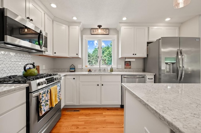 965 Main St, Wilbraham, MA 01095 - kitchen featuring appliances with stainless steel finishes, white cabinetry, recessed lighting, light wood-type flooring, and light stone countertops