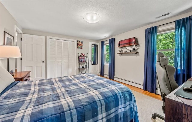 965 Main St, Wilbraham, MA 01095 - bedroom with multiple windows, light wood finished floors, baseboard heating, a textured ceiling, and a baseboard heating unit