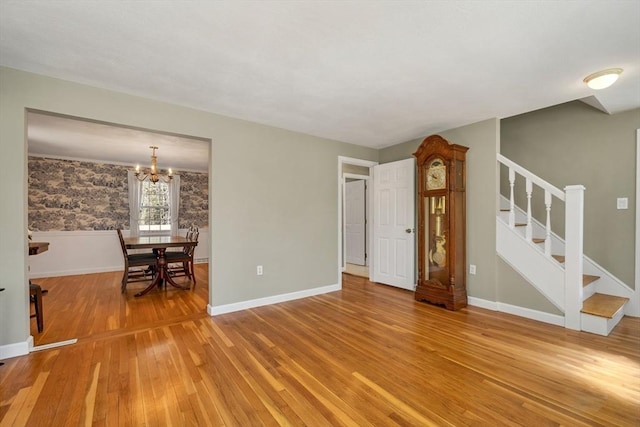 living room with baseboards, light wood-style flooring, a chandelier, and stairway
