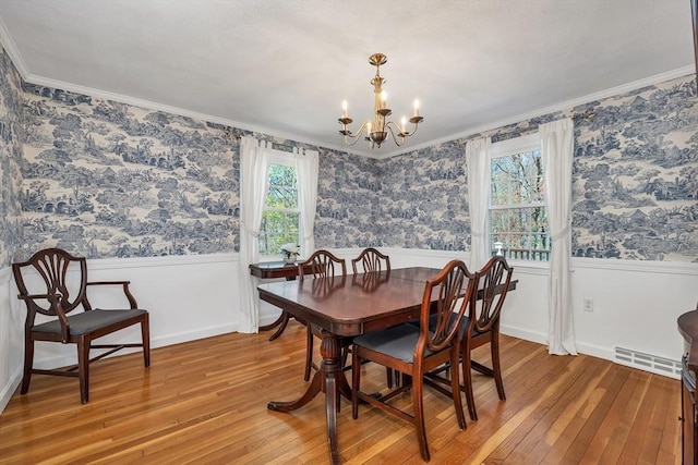 dining area featuring an inviting chandelier, wainscoting, and light wood finished floors
