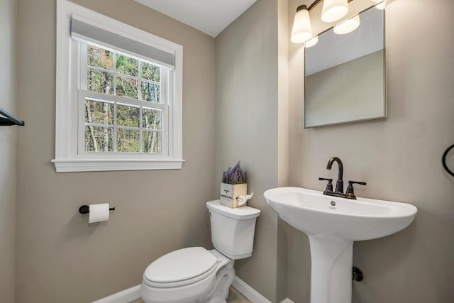 bathroom with a sink, baseboards, and toilet