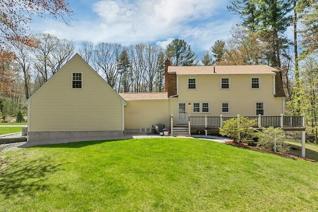 rear view of house featuring a chimney, a lawn, and a deck