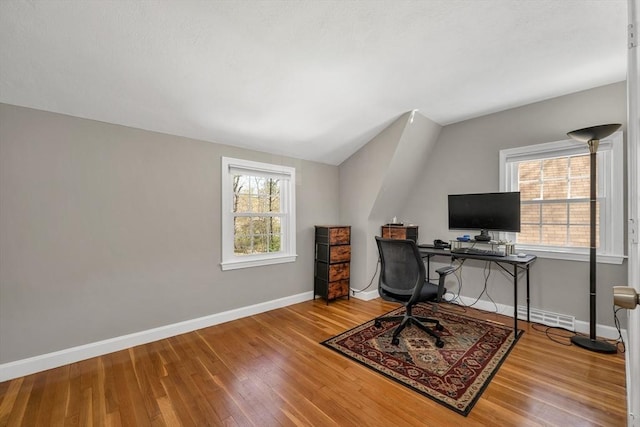 office space featuring baseboards, vaulted ceiling, and wood finished floors